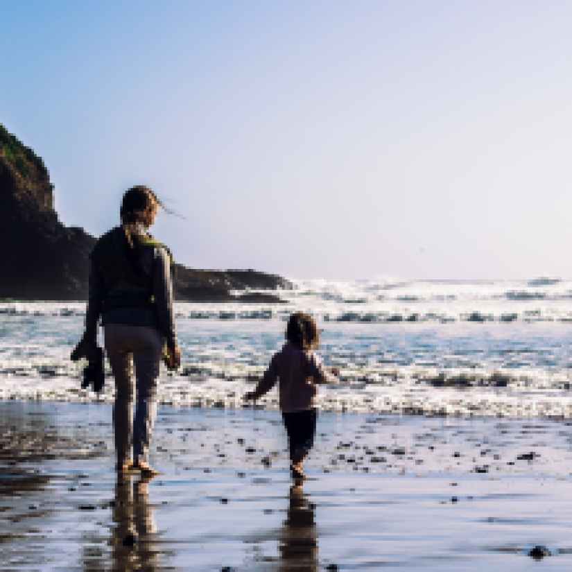 girl and toddler walking at the shore