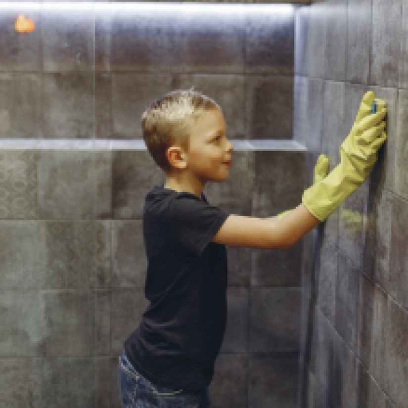 small child washing tiles in bathroom alone