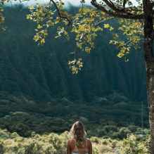 unrecognizable female meditating on grass in highlands on sunny day